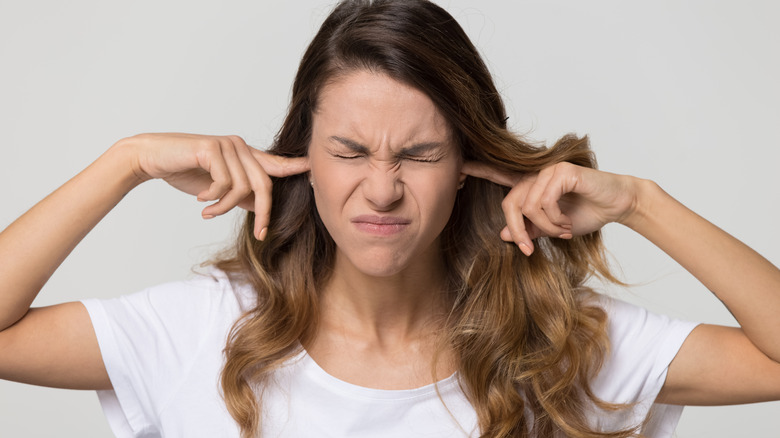 Woman plugs ears with fingers