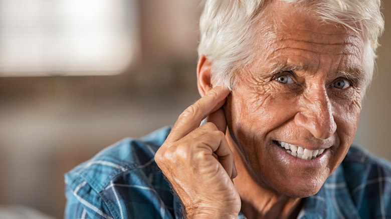 Man touches ear with fingers