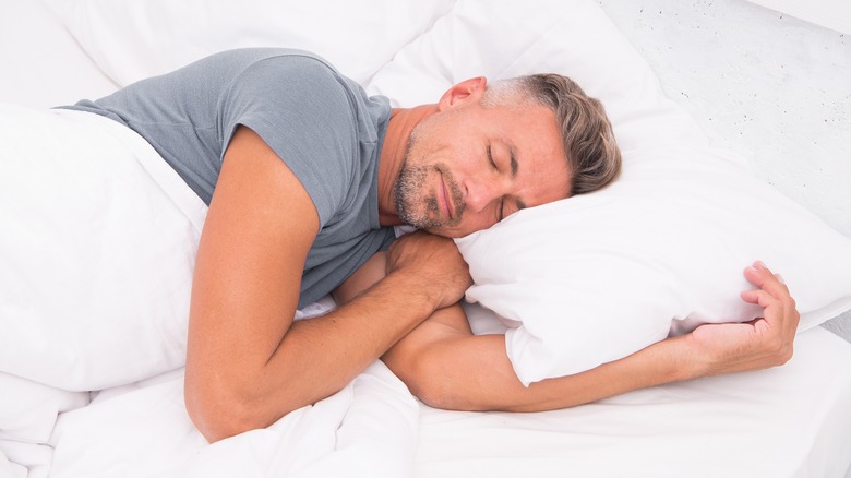 Man asleep on his side in a bed
