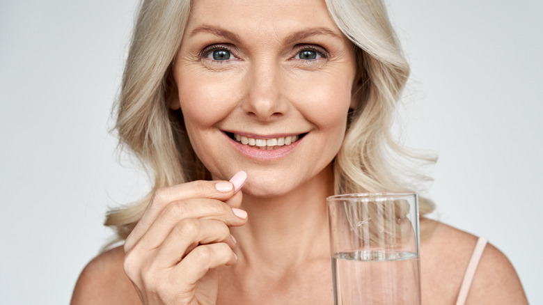 Woman with glass of water and pill