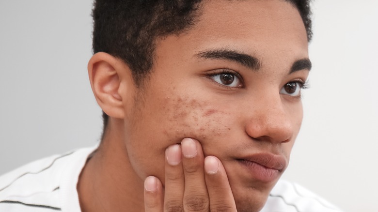a teenager looking at his face in the mirror
