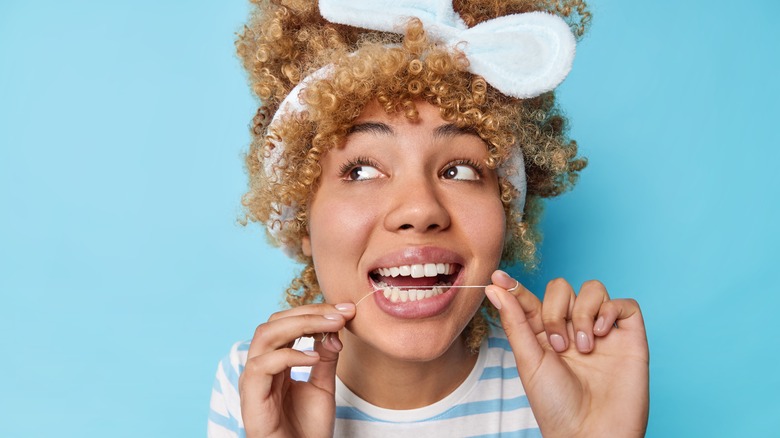 young woman flossing her teeth 