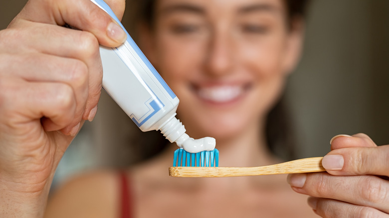 woman applying toothpaste to toothbrush