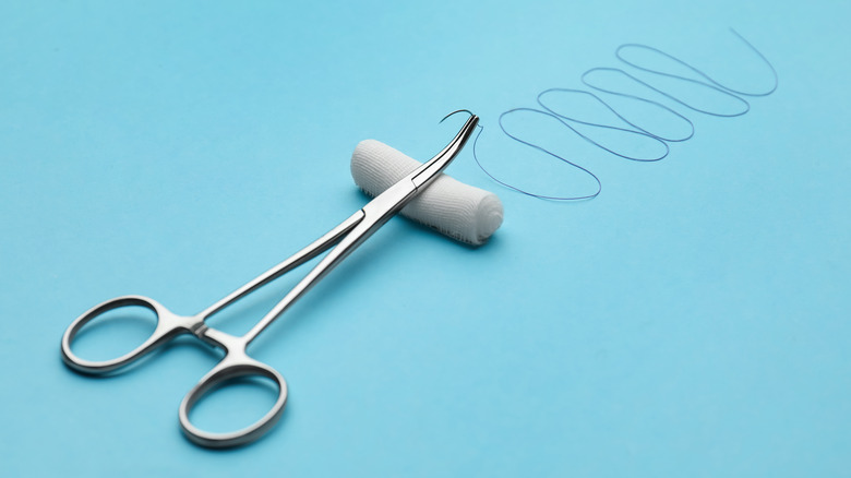 forceps and sutures on blue surface