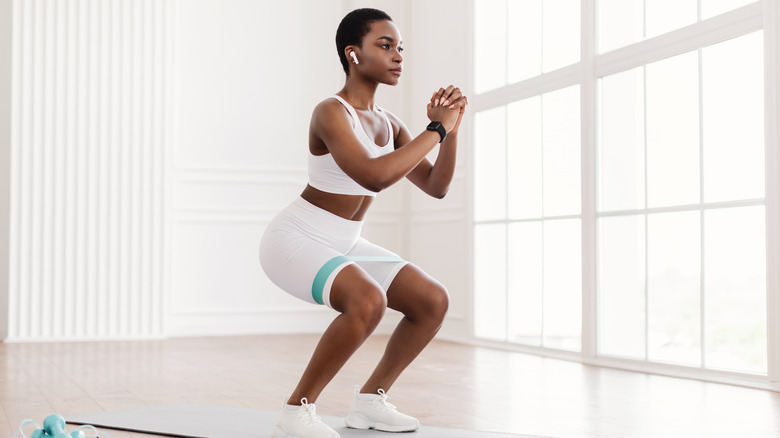 woman doing squats with a resistance band 