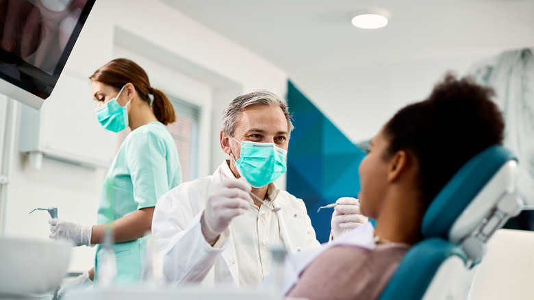 Woman in dentalchair with dentist and hygenist clsoe-by