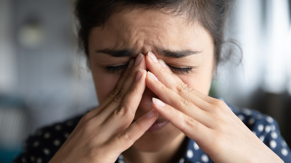 Woman with facial pain holding nose