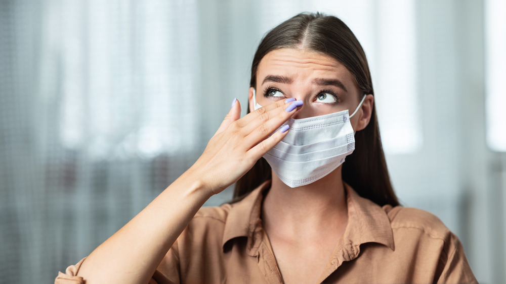 Girl in facemask rubbing her eye