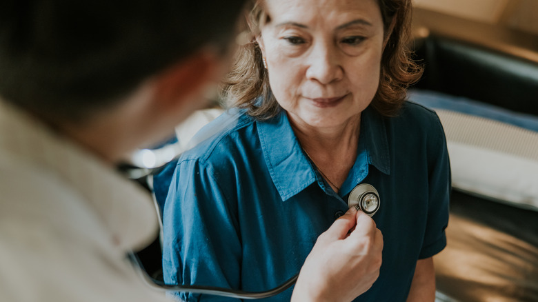 Doctor using stethoscope on patient