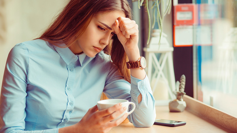 woman with headache drinking coffee