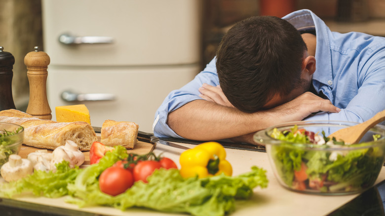 man with headache, making dinner