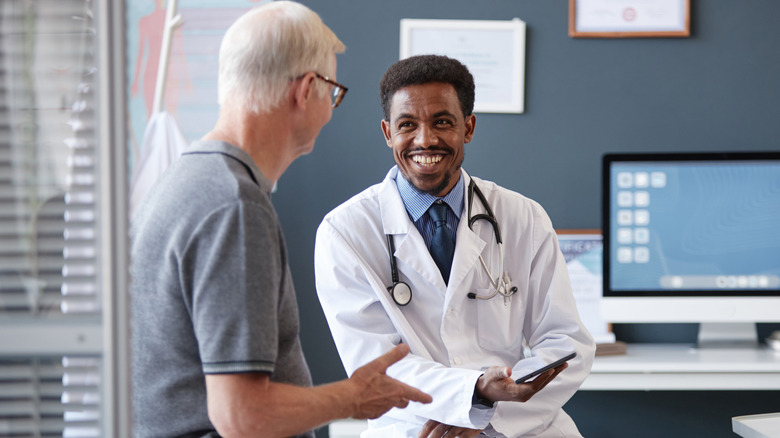 A man sitting in an examination room talking to his doctor