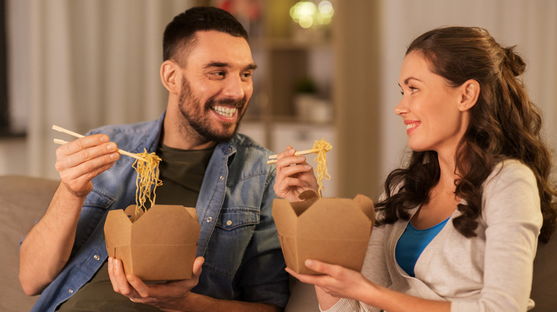 Couple eating takeout with chopsticks