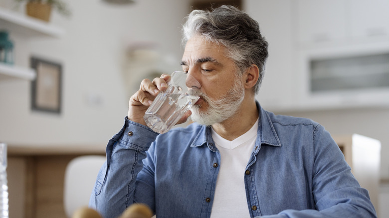 An older man drinking a glass of water at home