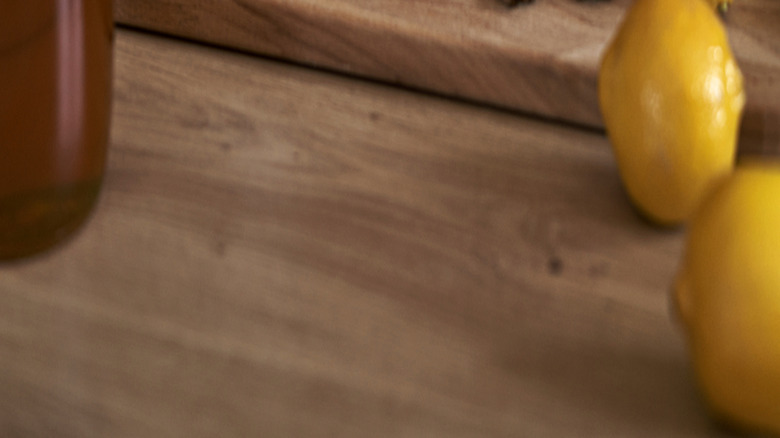 woman adding cloves to hot liquid with lemon slice