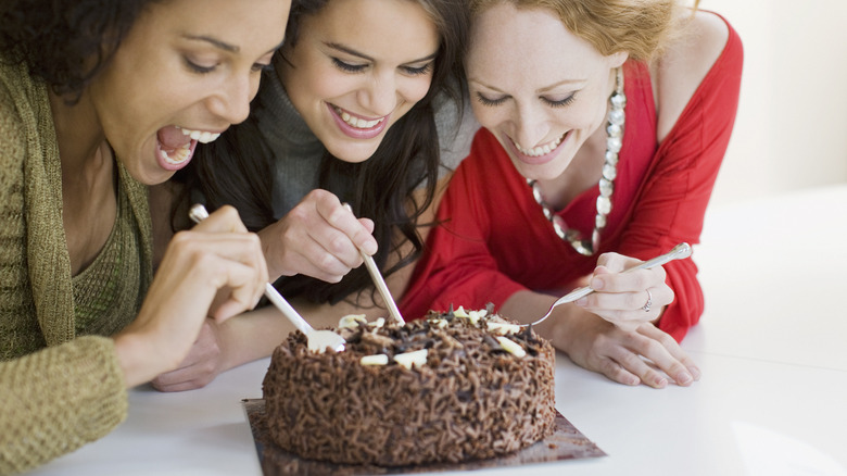 three women eating a cake