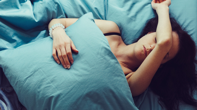 Sleeping woman hugging blue pillow