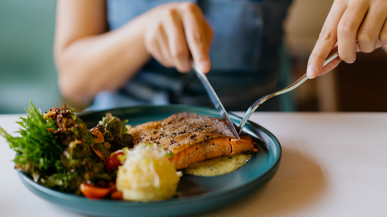 Utensils cutting into salmon filet