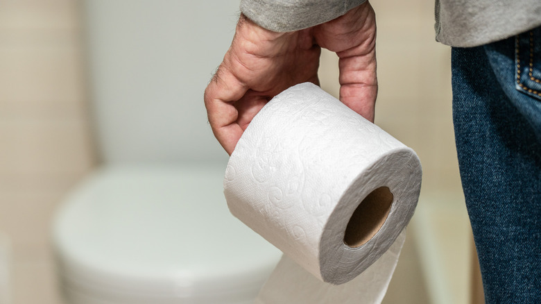 Man holding roll of toilet paper