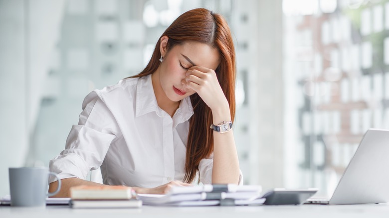 woman rubbing her sore eyes while at work