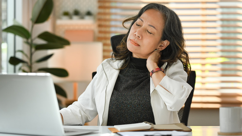 woman suffering from neck pain at her desk
