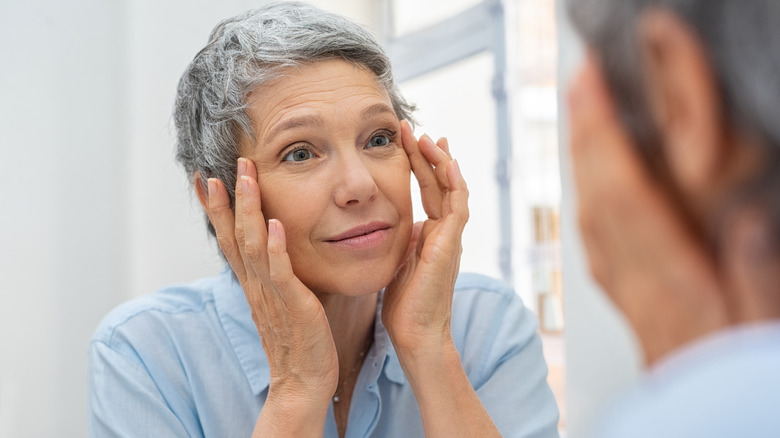Senior woman checks eyes in the mirror