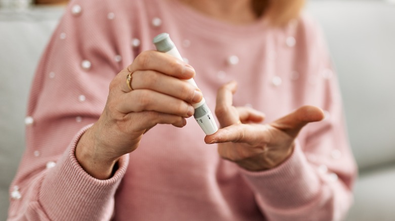 woman testing finger with glucometer