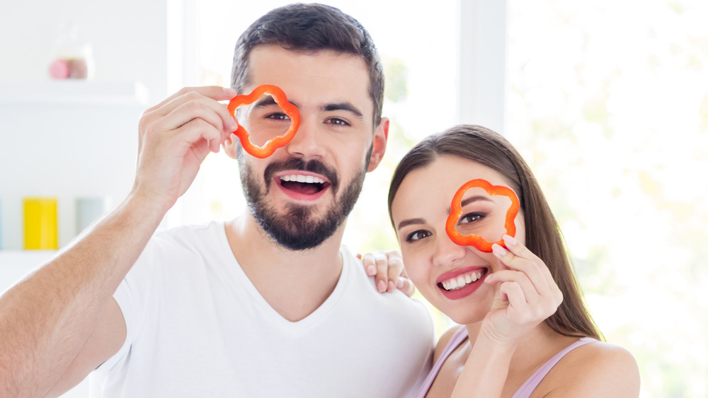 man and woman holding up pepper slices