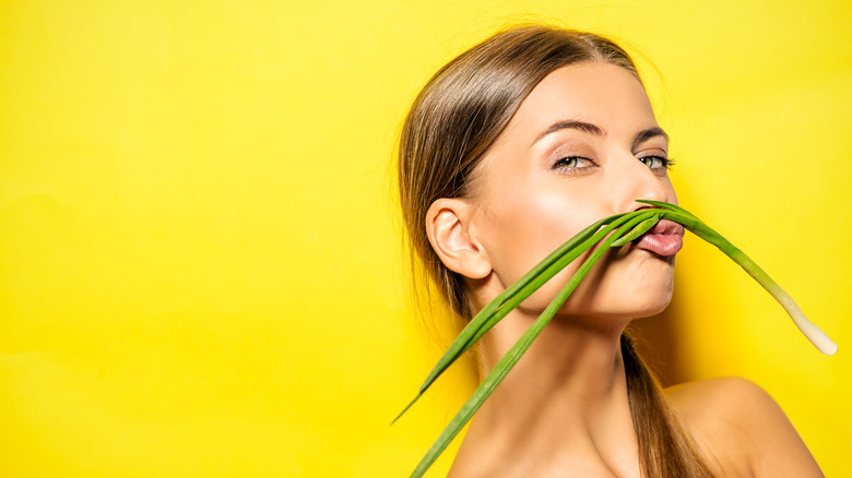 woman with green onion on face