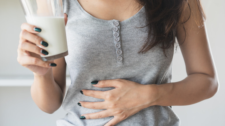 woman touching stomach while holding glass