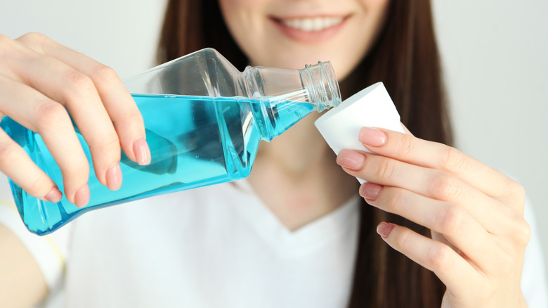 Person pour mouthwash into its lid