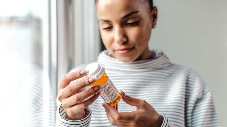 Woman looking at medicine bottle