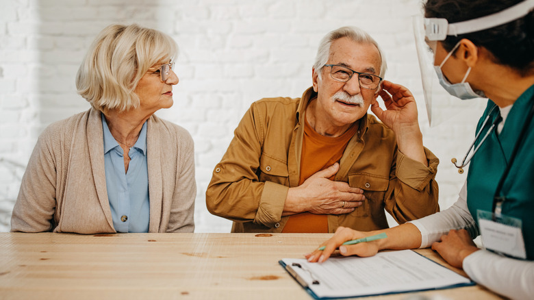 senior couple talking with health worker