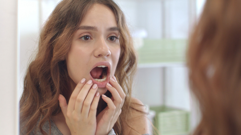 woman looking at her teeth in the mirror