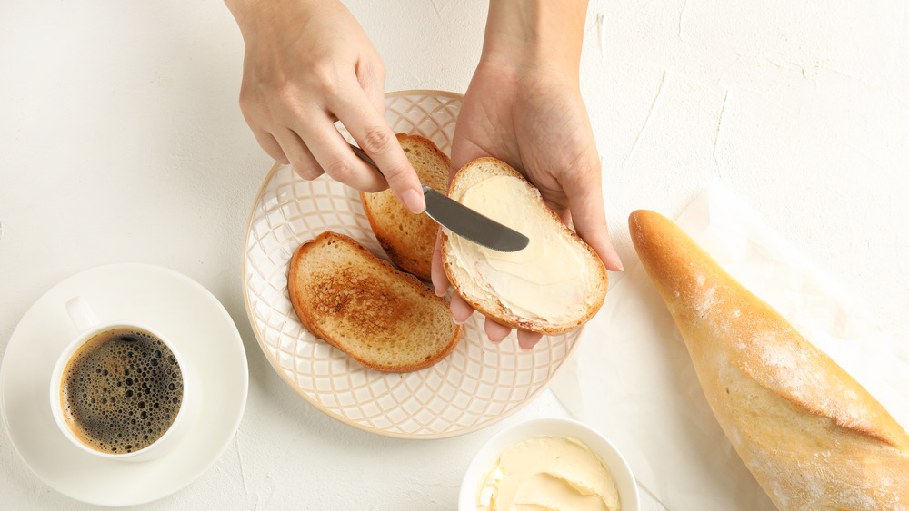 woman buttering toast, cup of coffee