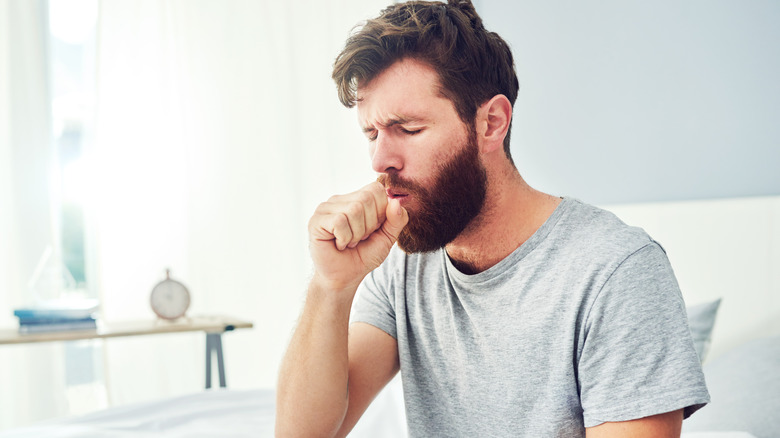 man sitting up and coughing