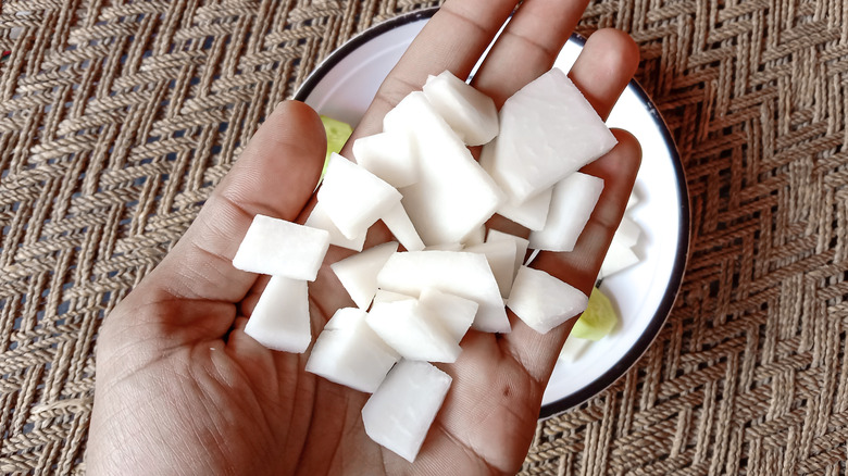 man's hand holding diced turnips