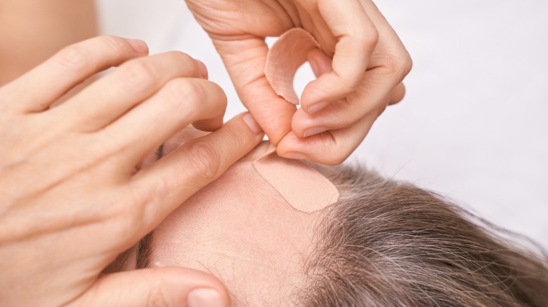 Hands placing bandage on face