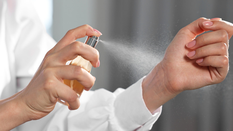 Woman spraying perfume onto her wrist while indoors