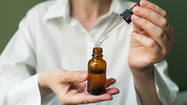Hands holding essential oils dropper