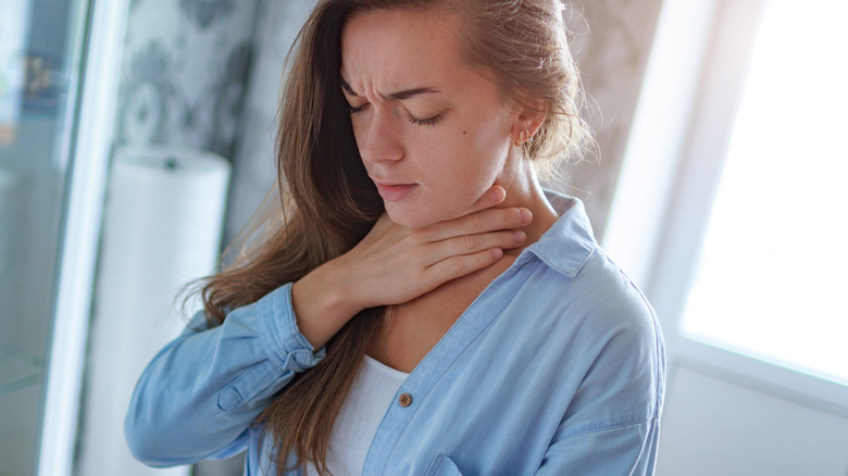 Woman placing hand on her neck