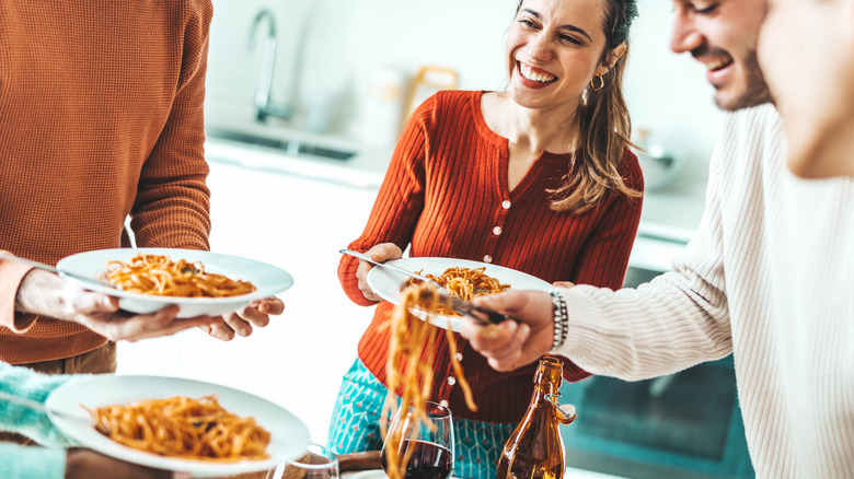 Friends eating pasta together at home