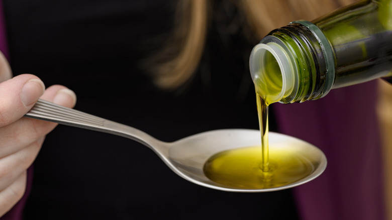 woman's hand pouring olive oil on spoon