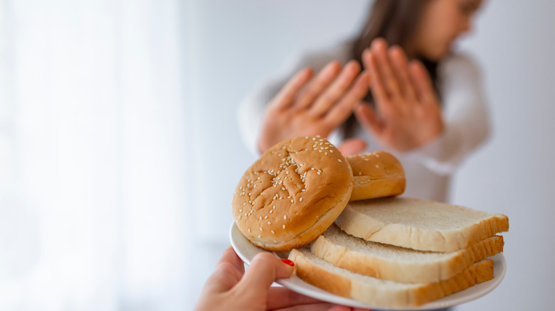 woman pushing away bread on a plate