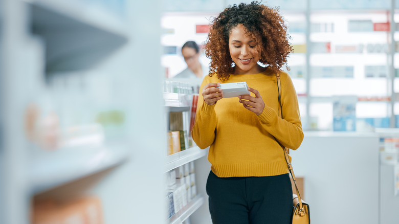 woman looking at box at pharmacy