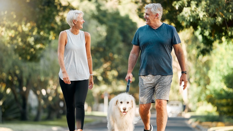 older adults walking dog outdoors