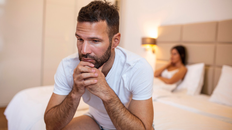 Worried man in bed with upset woman