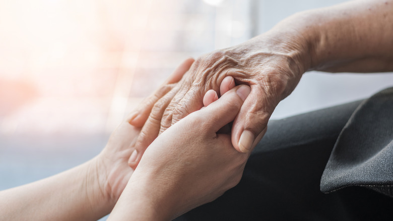 Young hands holding Alzheimer's patient's hand