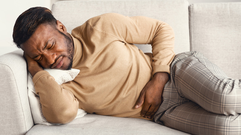 Man lying on the couch in pain
