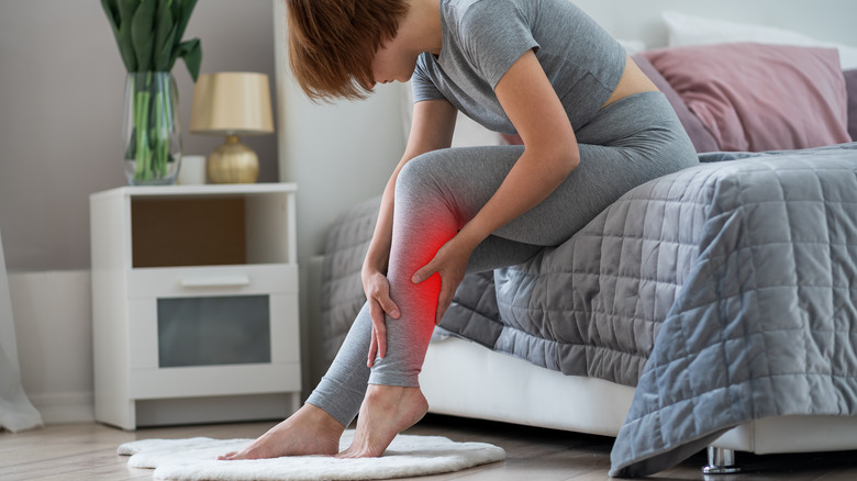 Person sitting on a bed holding her leg